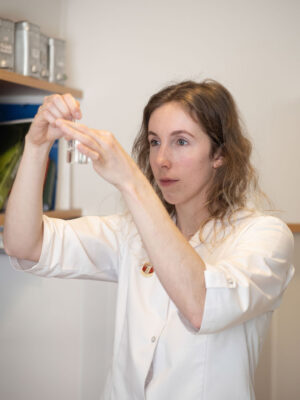 Apothekerin inspiziert zwei kleine Fläschchen mit einer Flüssigkeit.