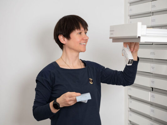 Apothekerin entnimmt ein Medikament aus einer Schublade in der Apotheke.